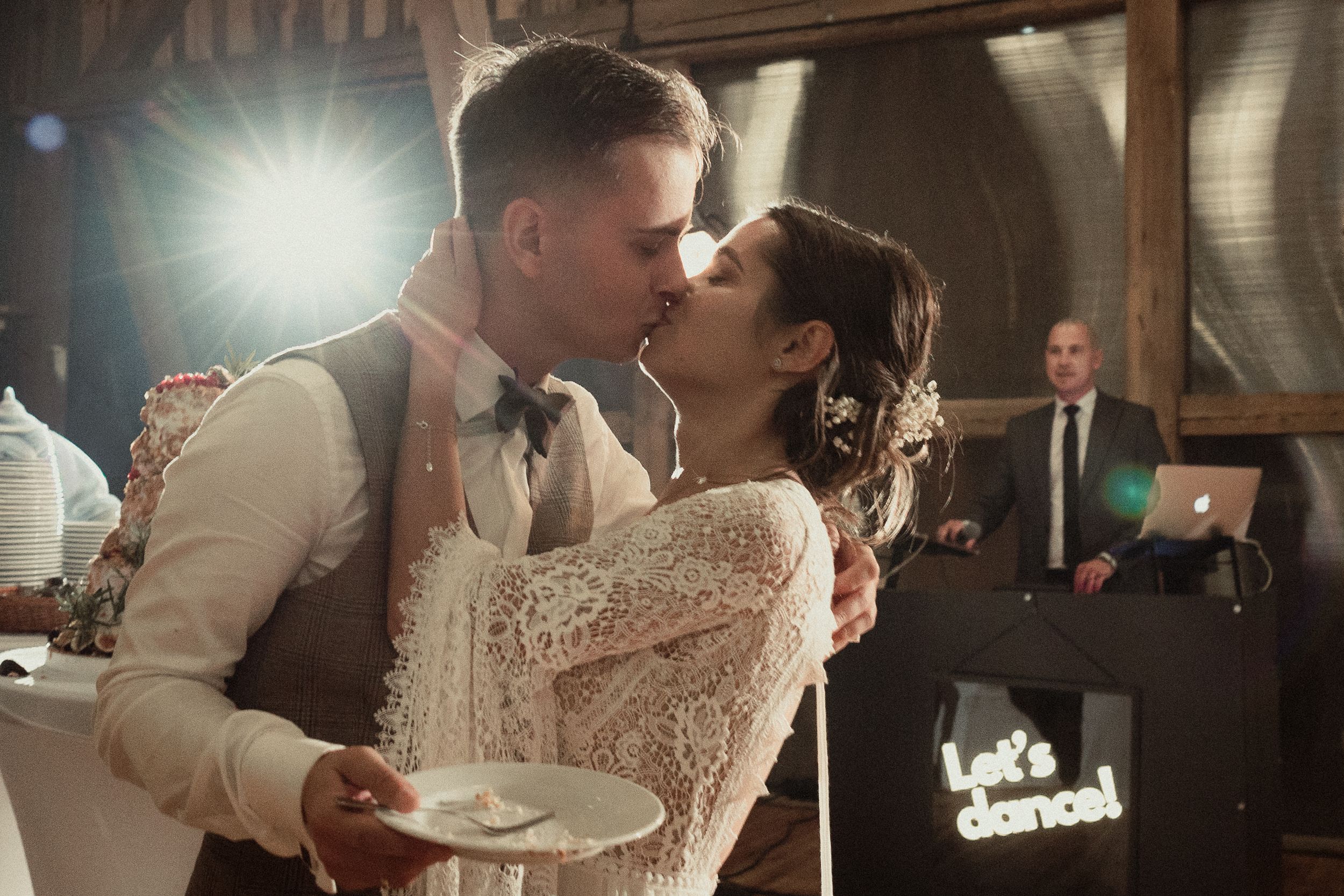 Two newlyweds share an intimate moment during their first dance at a dimly lit wedding reception.