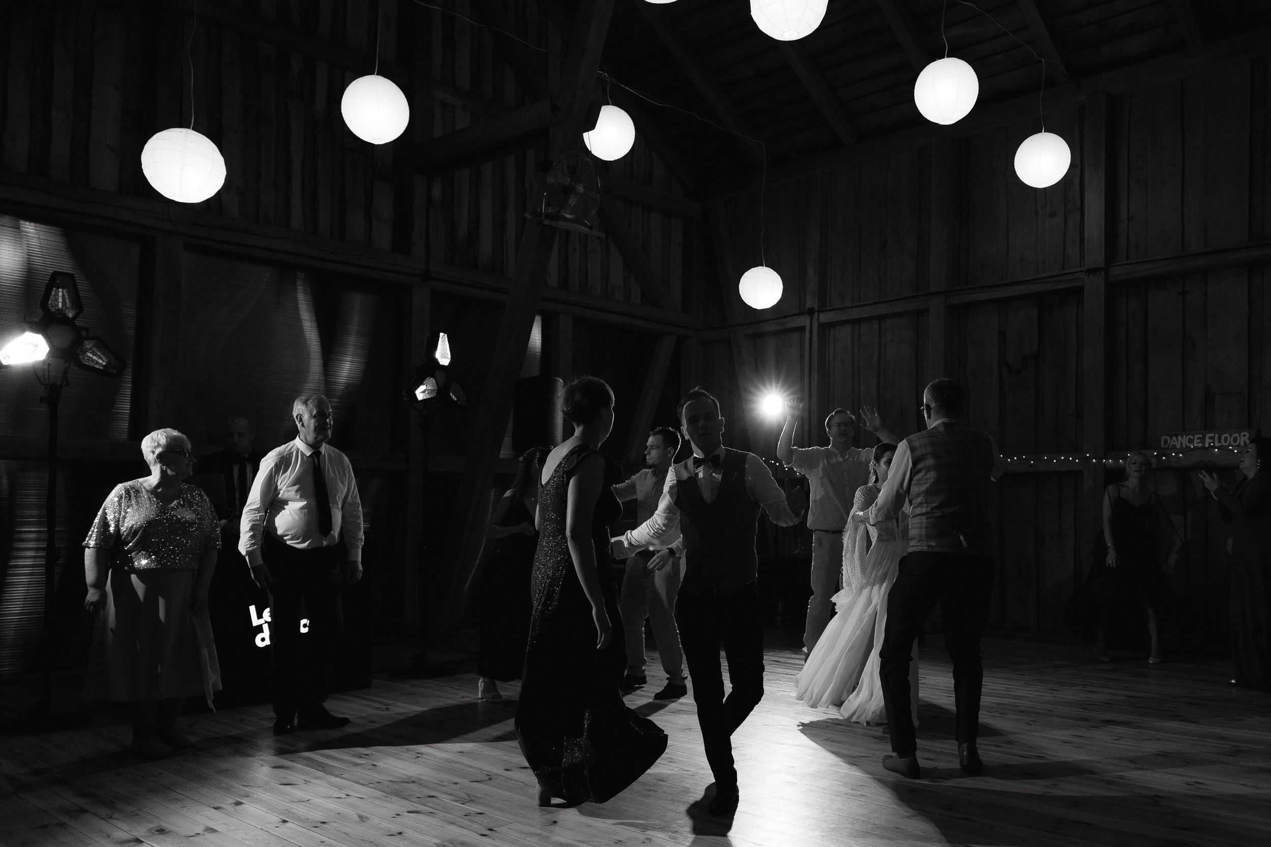 Dark silhouettes of dancers move across a dimly lit stage during a dramatic contemporary performance.