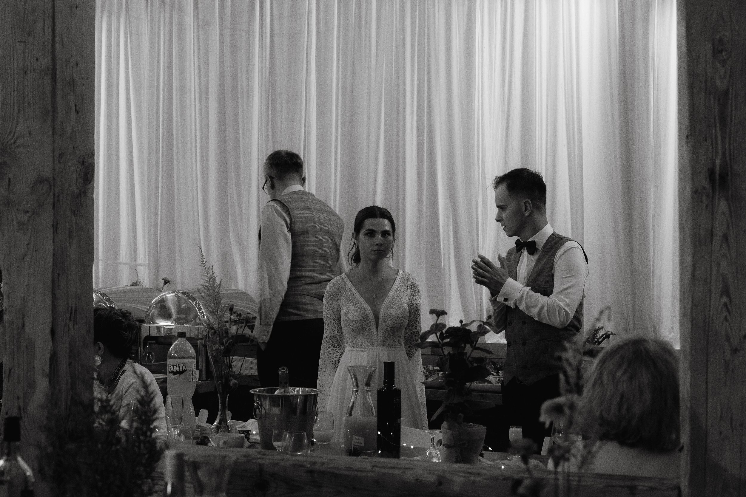 Black and white photograph showing a formal dining event with people seated at tables with decorative centerpieces.