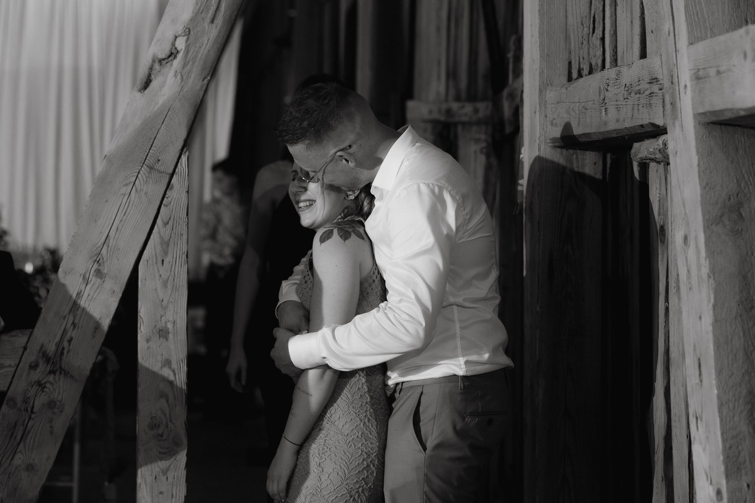 Vintage black and white photograph of two people in an intimate embrace near a doorway.