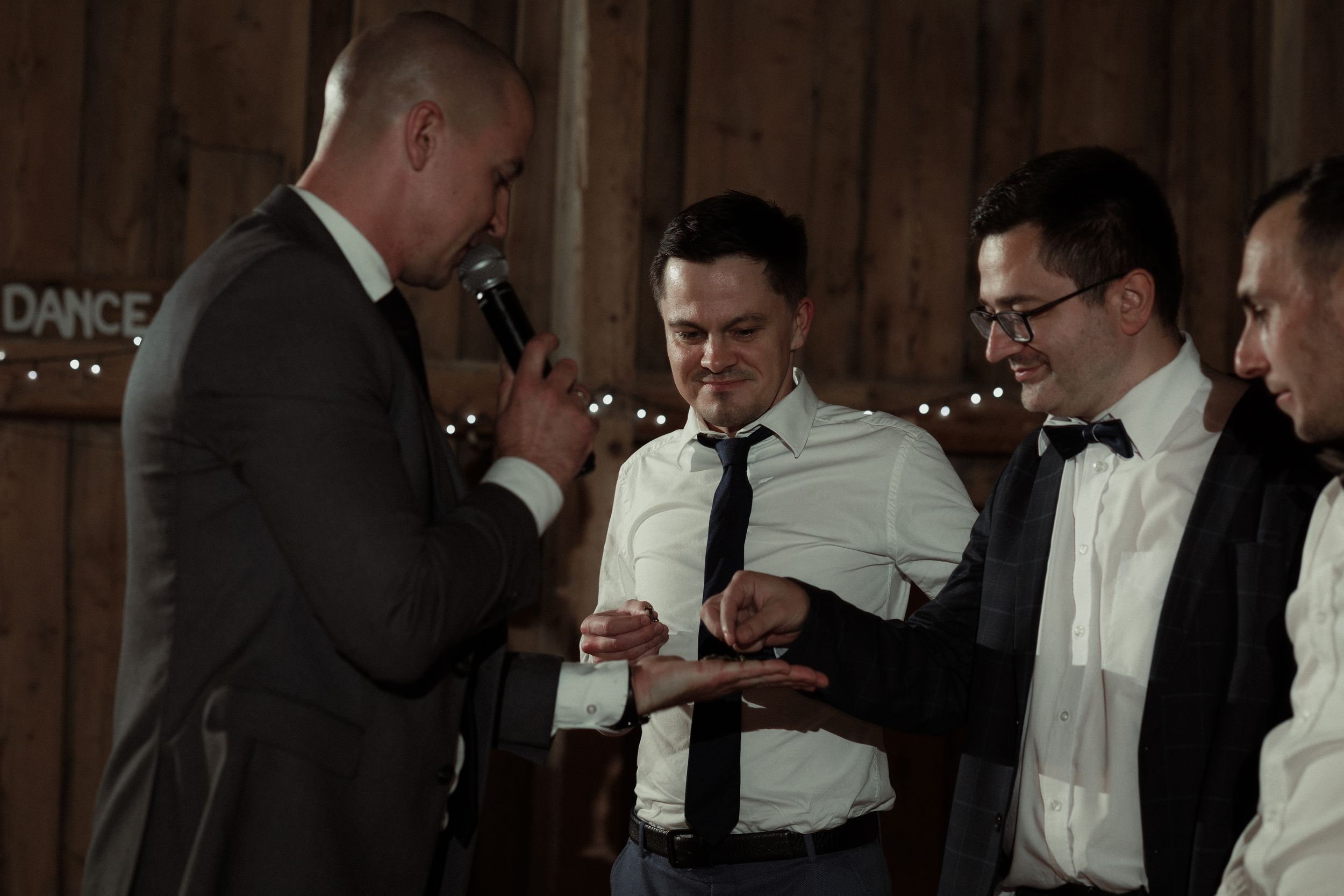Dancers and guests mingle near a bar at an elegant evening reception with string lights overhead.