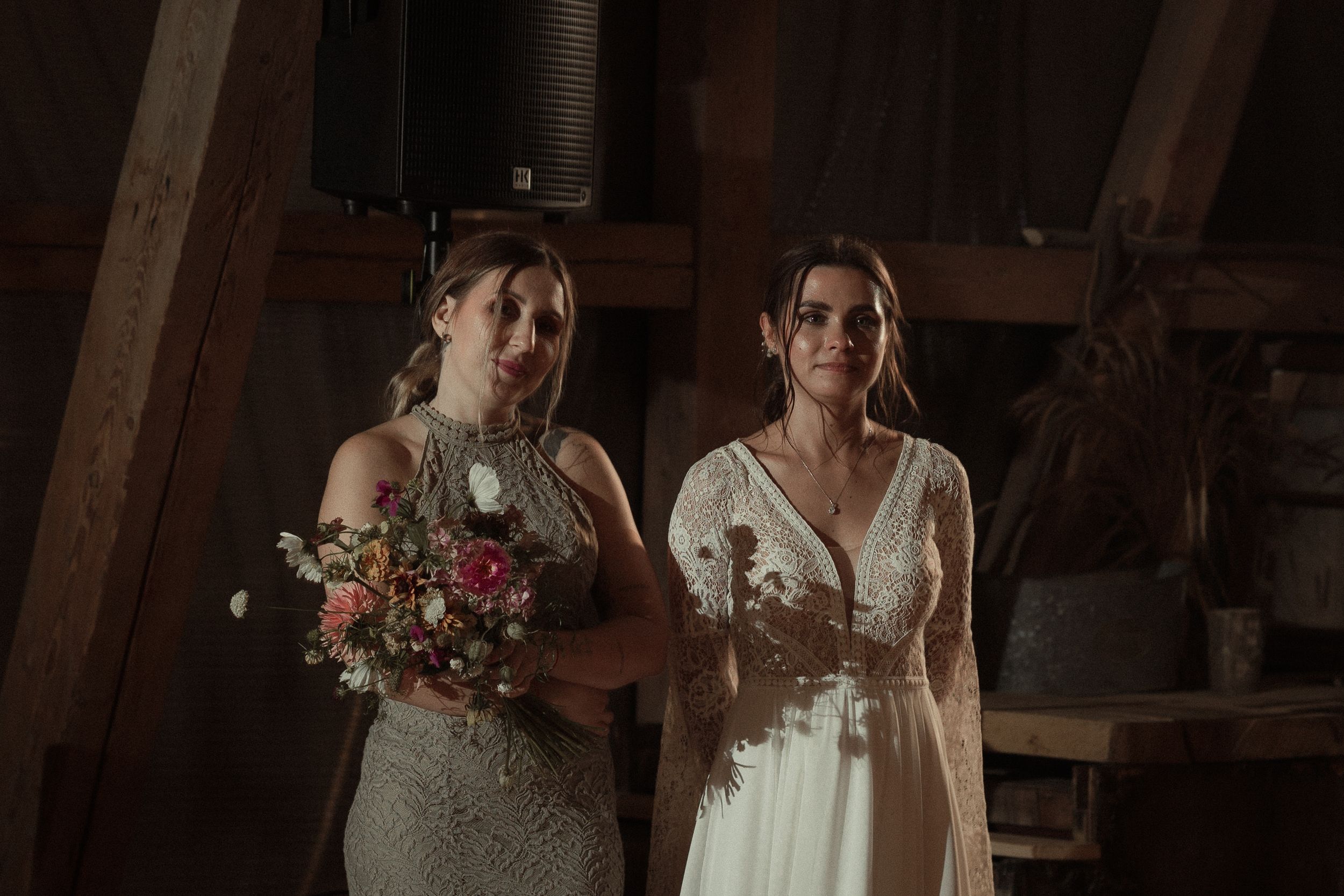 A couple shares an intimate moment in formalwear at a rustic venue illuminated by warm lighting.