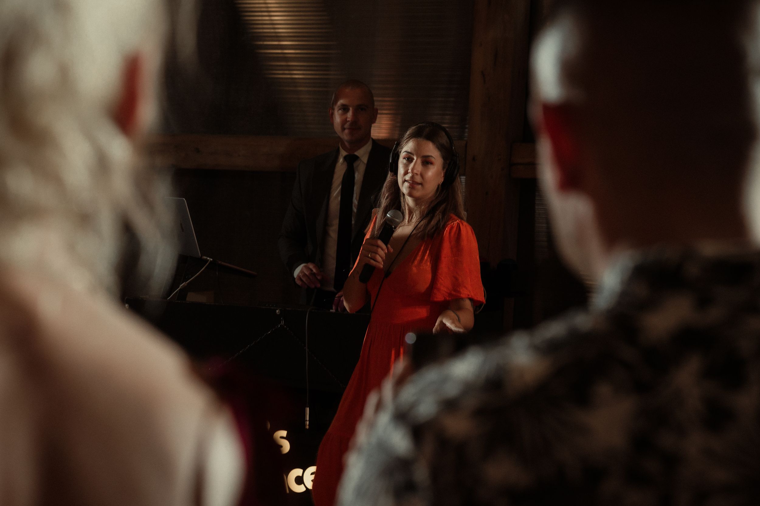 People in formal evening attire mingle during an elegant dimly lit indoor event.