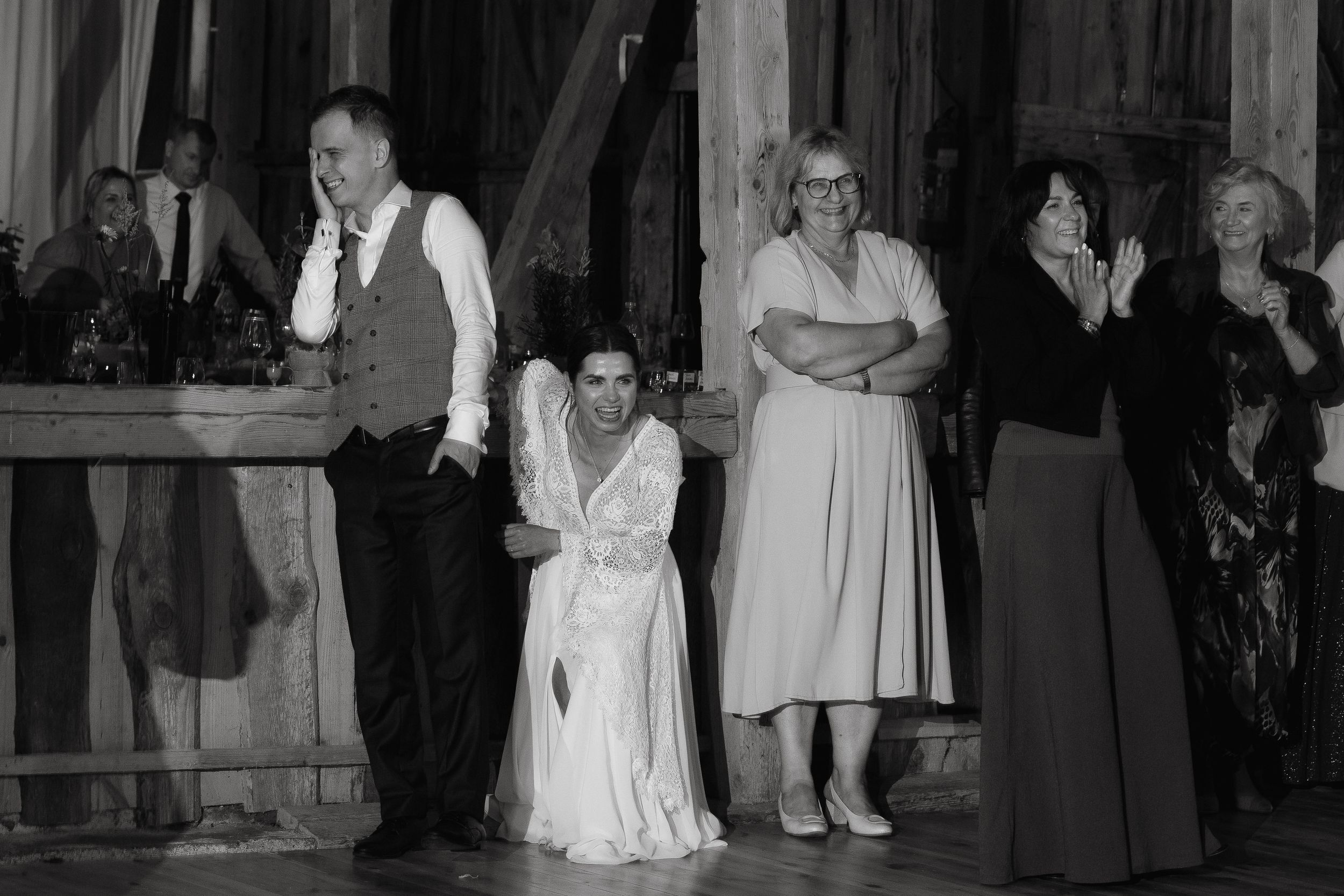 Wedding party guests dance together on a dance floor during an evening reception celebration.