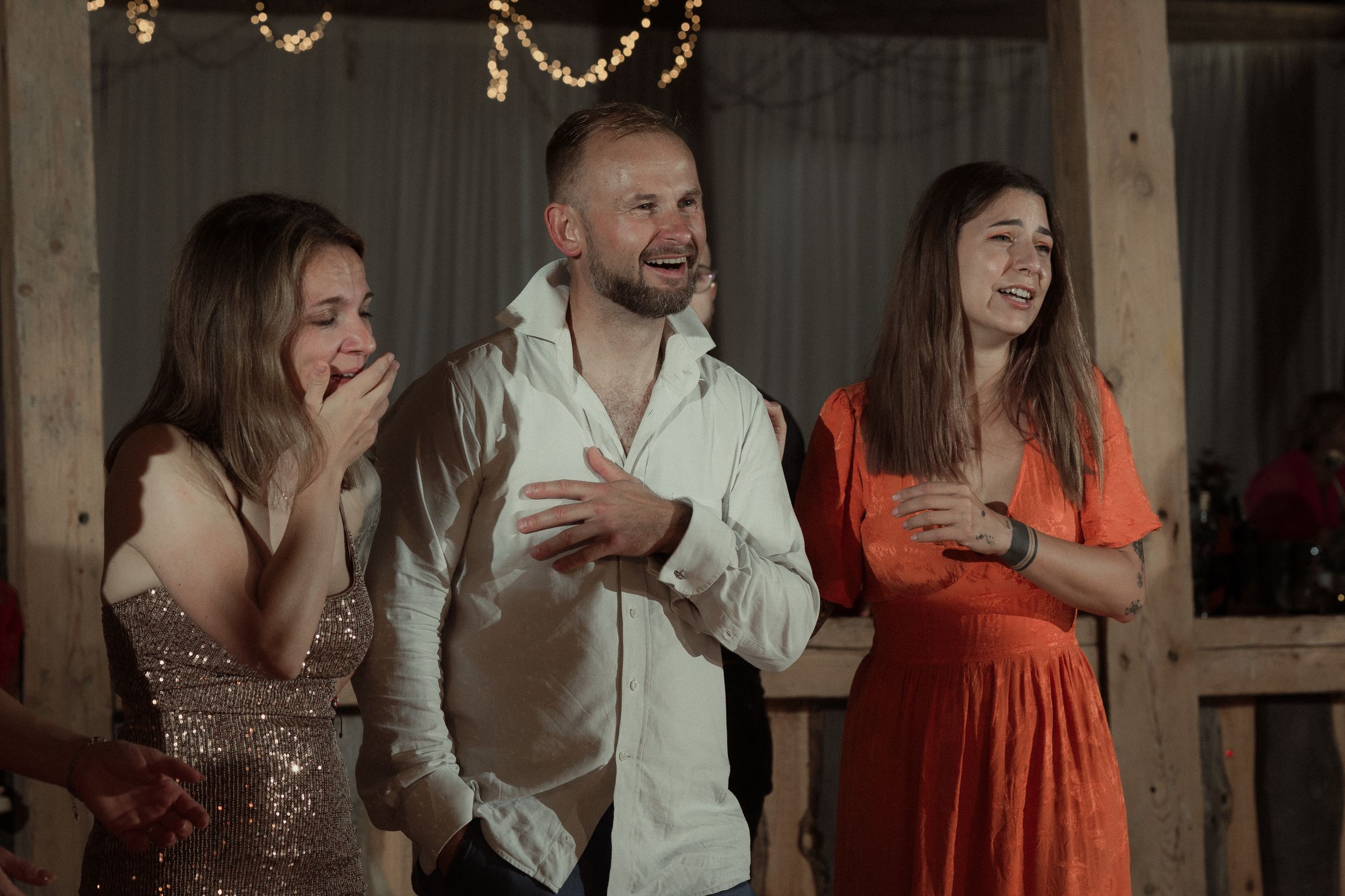 A group in formal attire celebrates at what appears to be a wedding party or special event gathering.