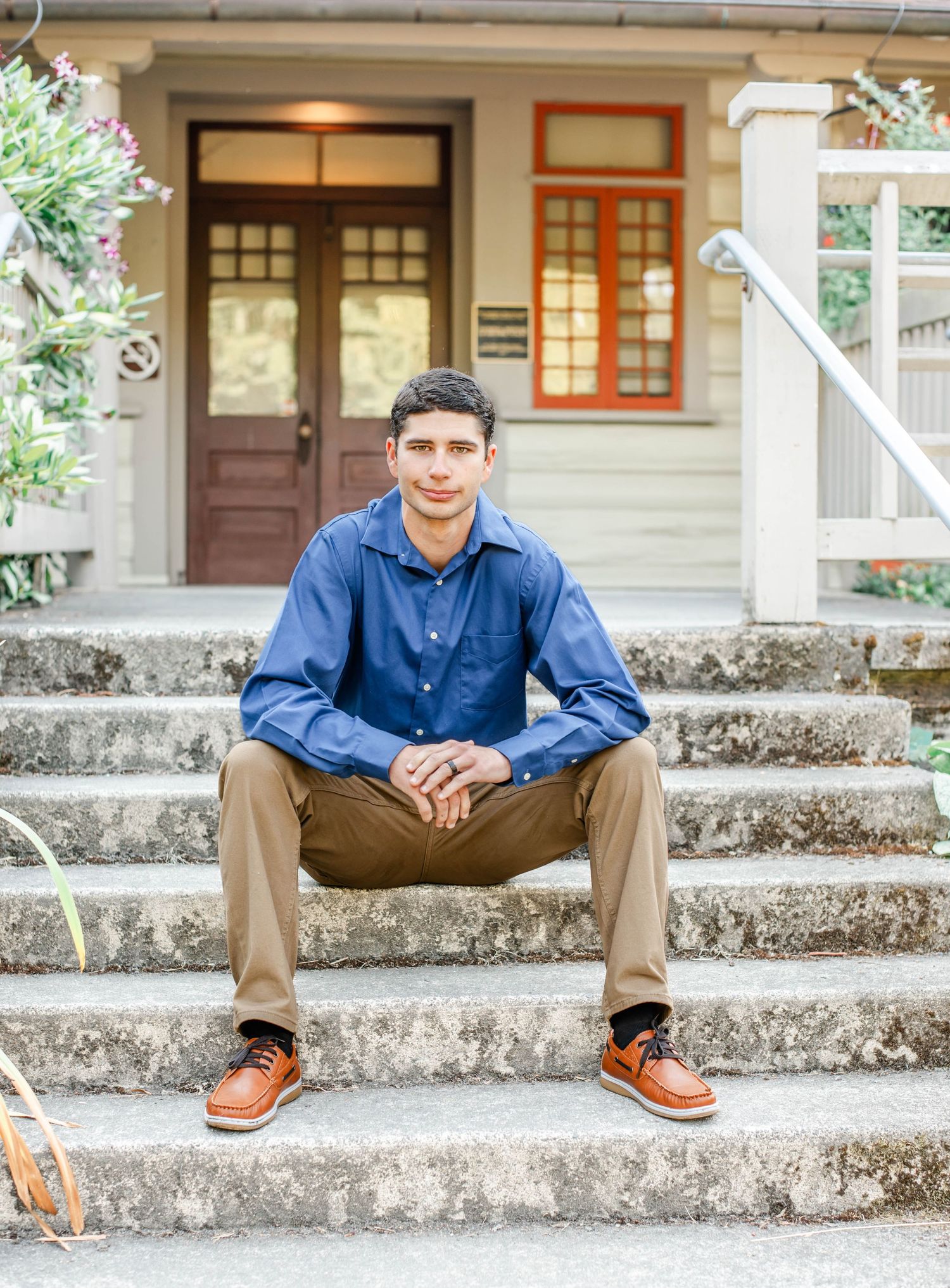 Casual poses on concrete steps outside a traditional building with wooden doors.