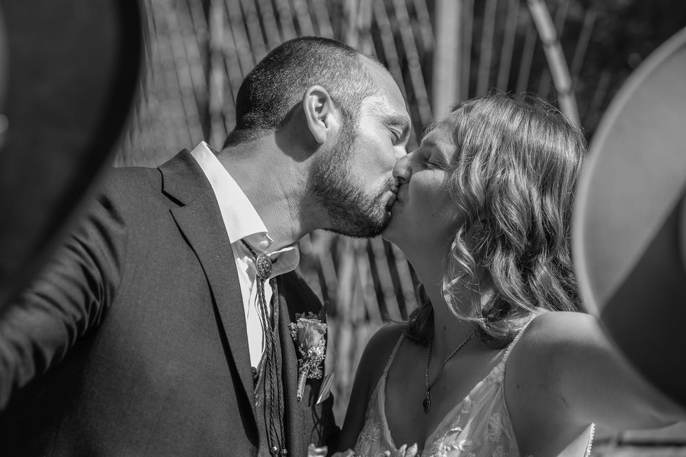 A romantic black and white portrait captures an intimate wedding day kiss.