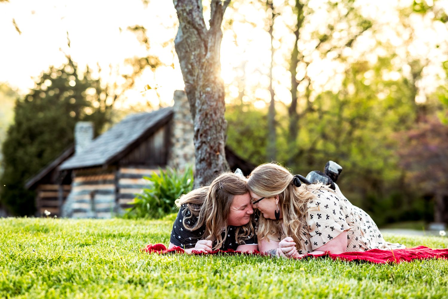 A couple wrapped in a red blanket share a tender moment together against a red door.