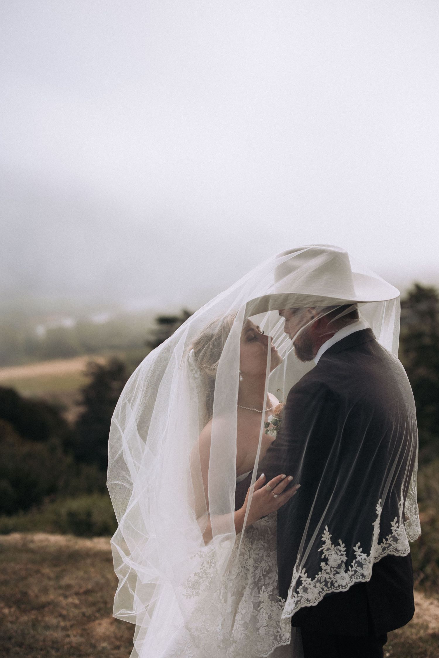 Bride and groom standing near a cliffside overlooking the coast in Northern California