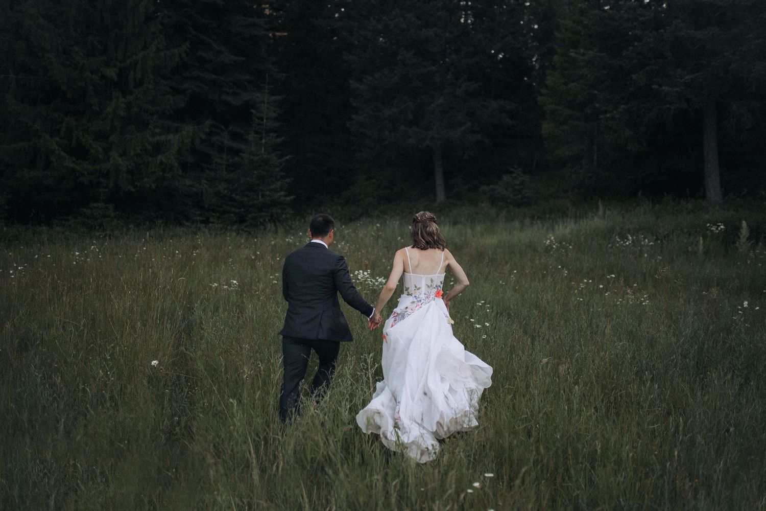 Bride and groom walking together in a wide-open Idaho field at sunset