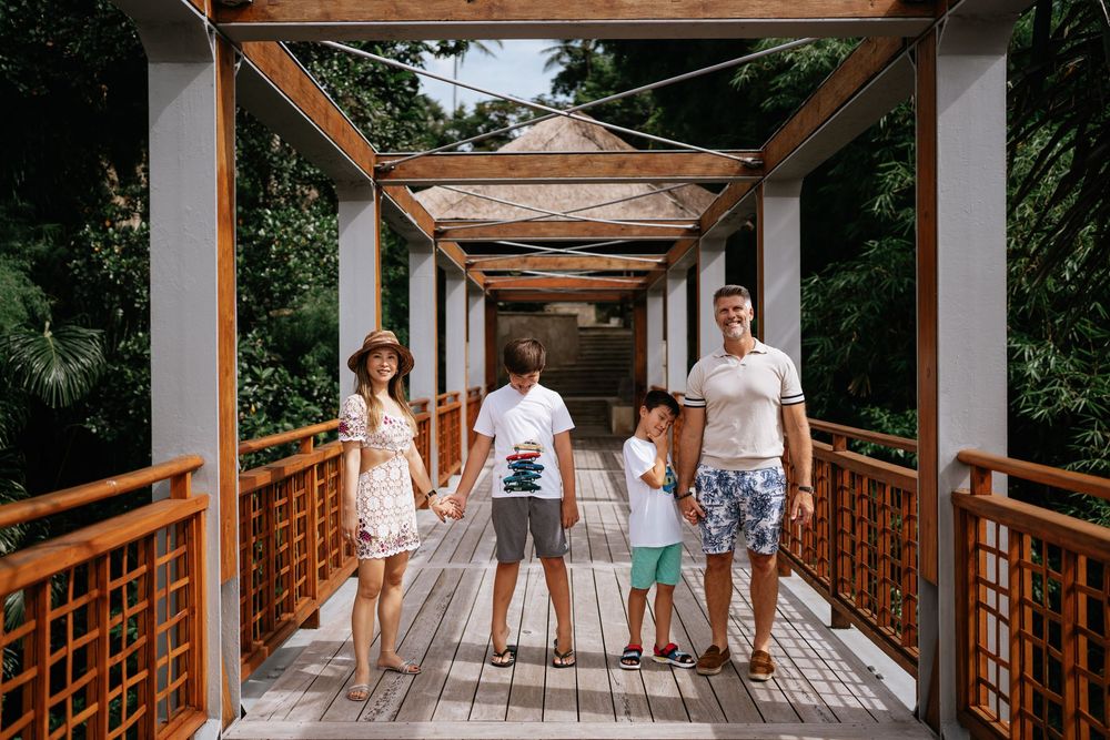 Family enjoying time together on a covered wooden walkway in a tropical setting.