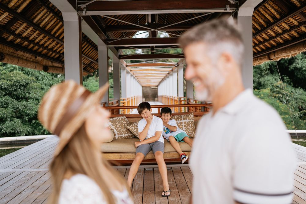 Relaxed family scene on a covered wooden deck with traditional architecture.