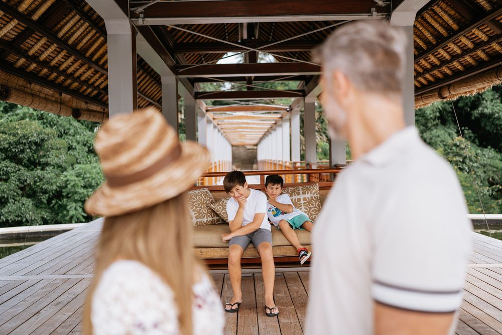 Tropical pavilion interior with family members and wooden benches creating depth perspective.