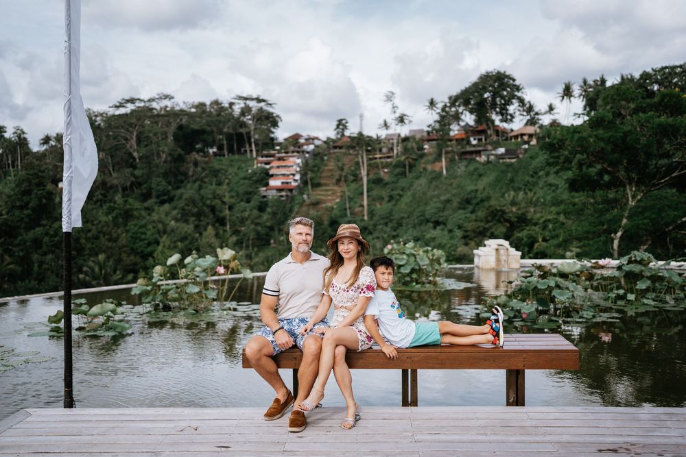 Family sitting on wooden deck overlooking a serene lake with hillside views.