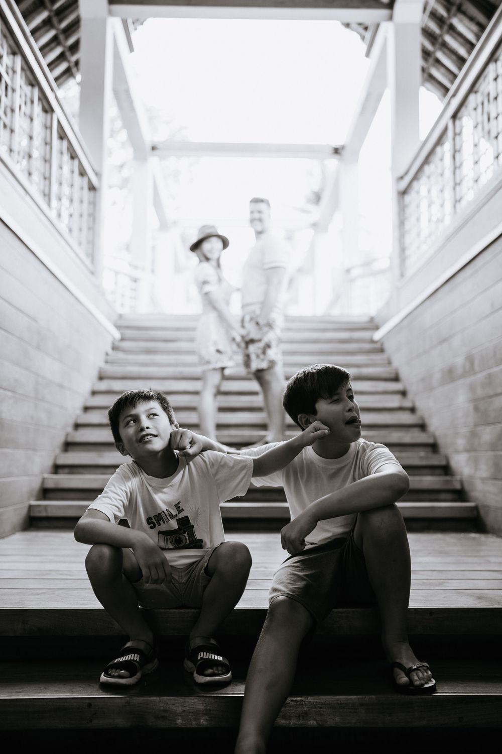 Two children sitting on stone steps in dramatic black and white composition.