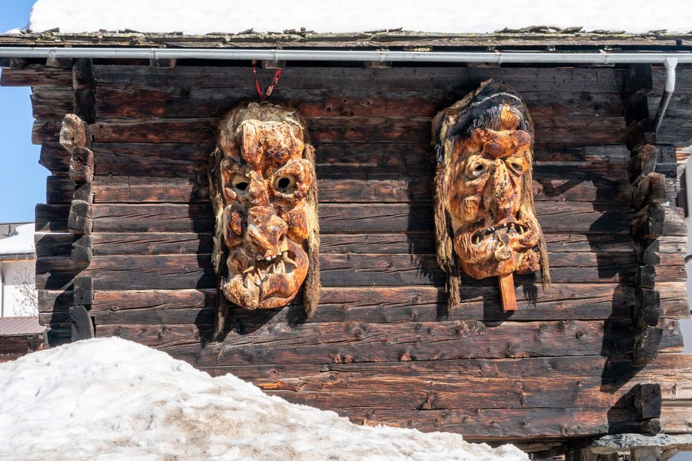 Weathered wooden alpine building with traditional carved decorative elements along its rustic facade.