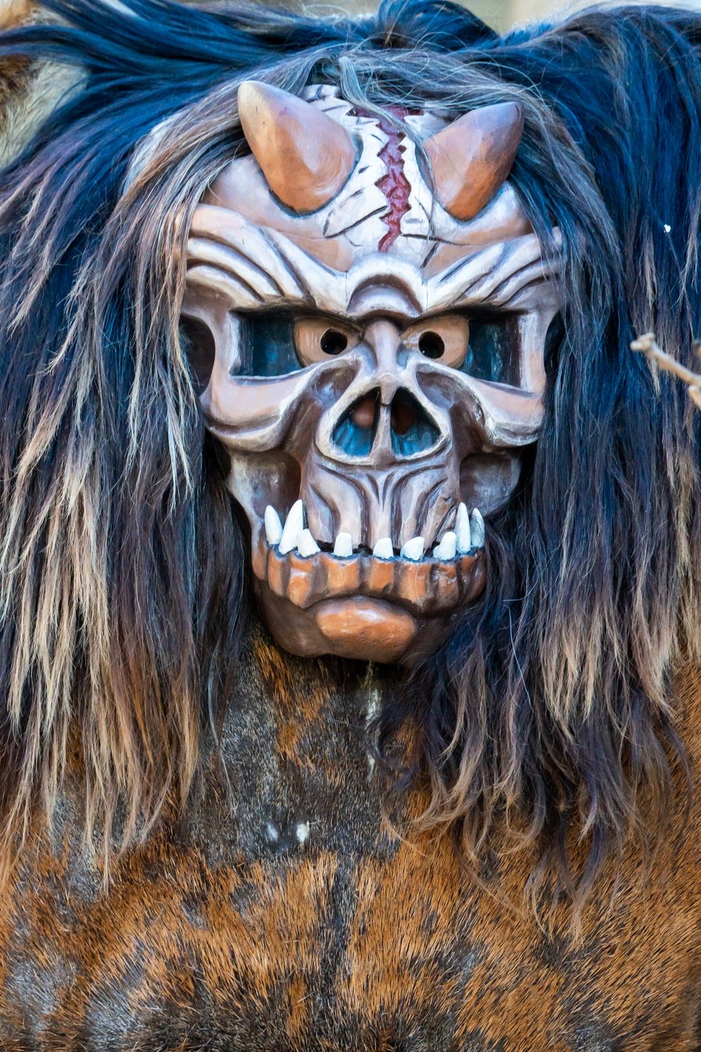 Close-up view of traditional indigenous ceremonial masks with blue hair and skull-like features displayed in sequence.