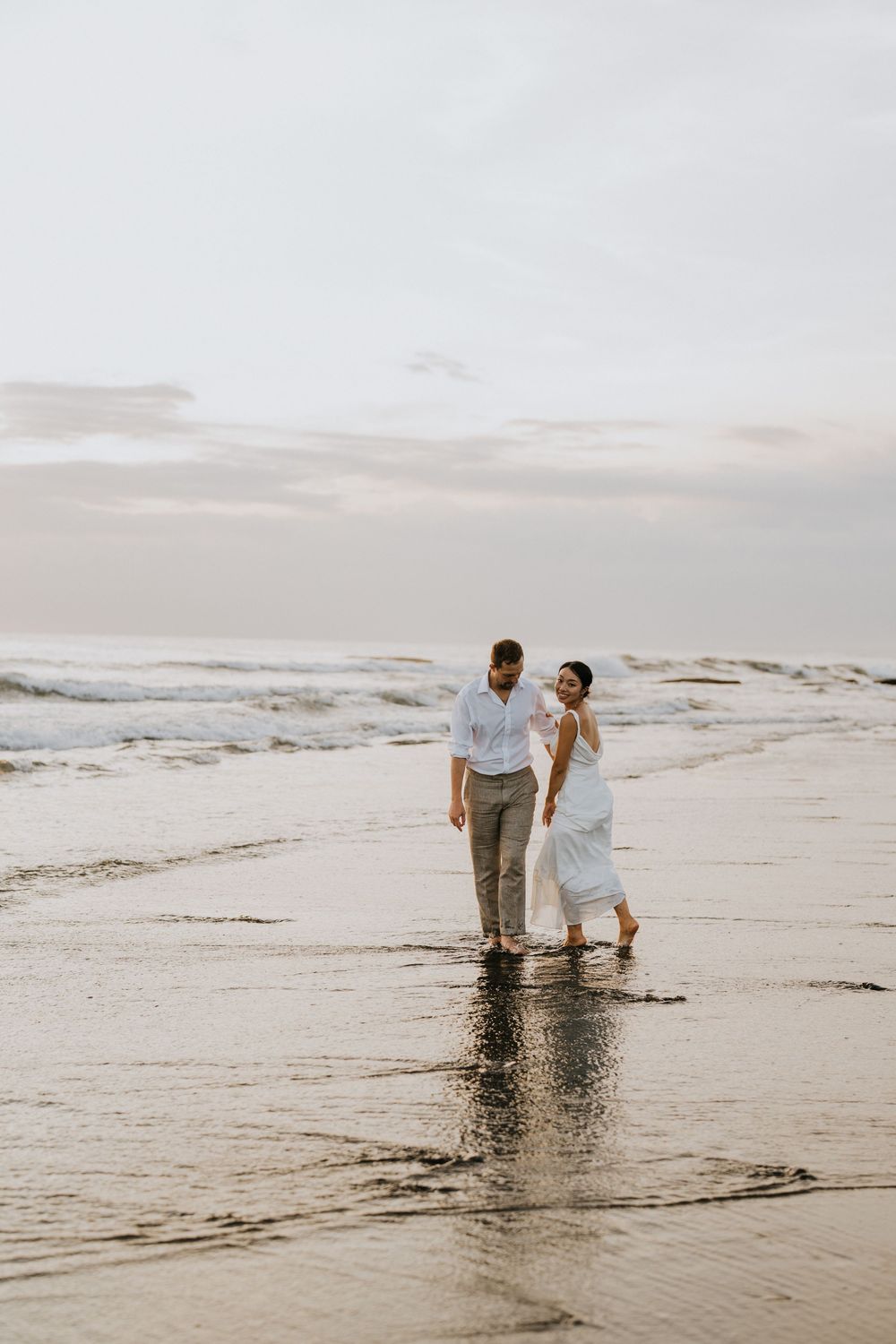 Romantic beach walk at sunset with waves lapping at their feet.