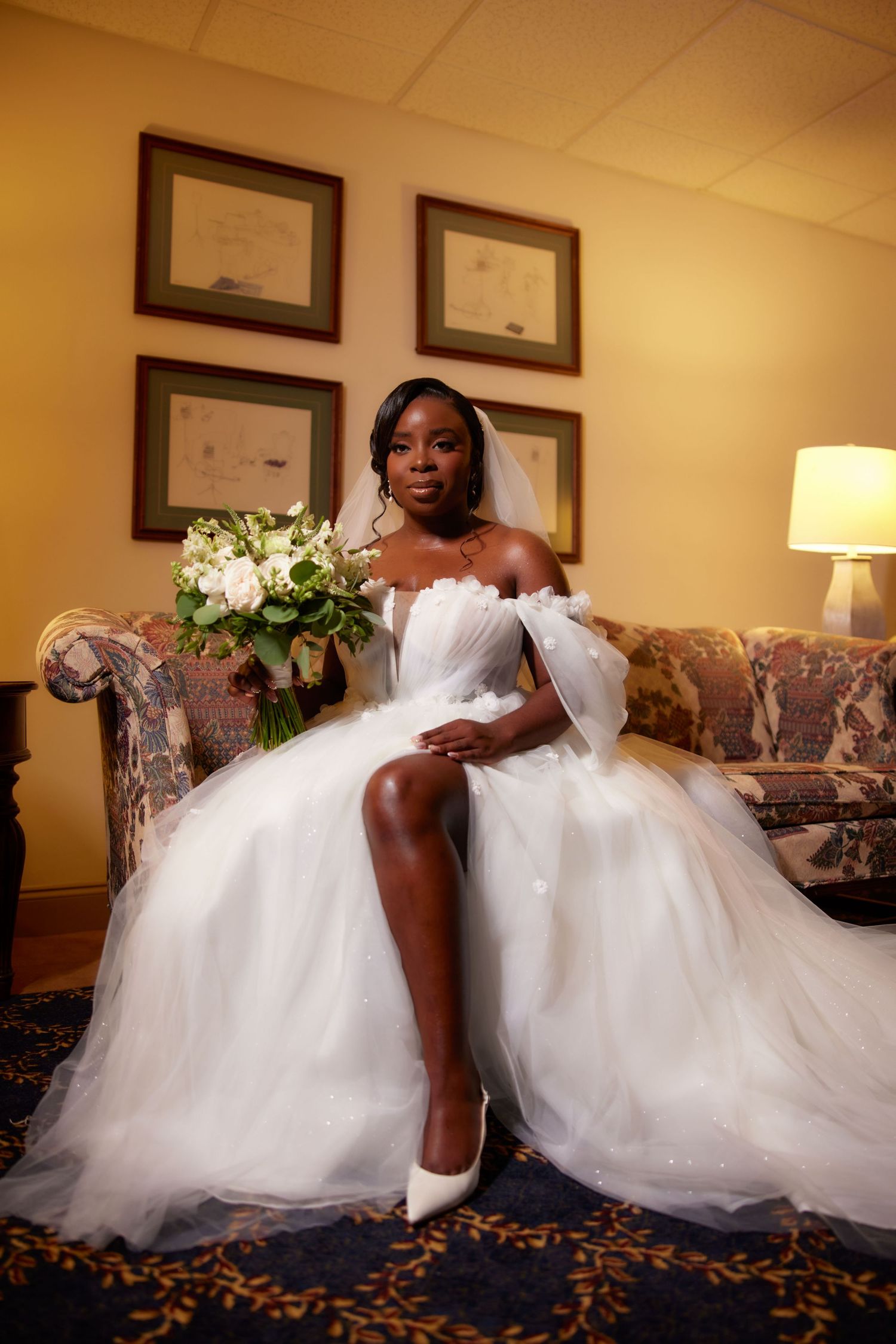 A romantic photo series showing a bride in a flowing white tulle gown reclining on a blue velvet sofa.