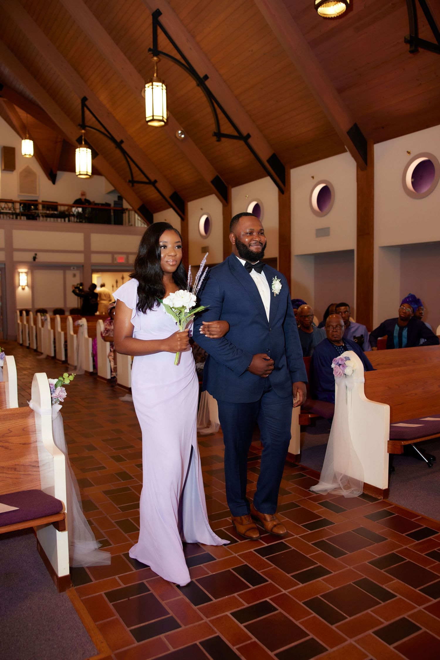 Wedding couple makes their grand entrance into an elegant church venue with exposed wood beams and terracotta floors.