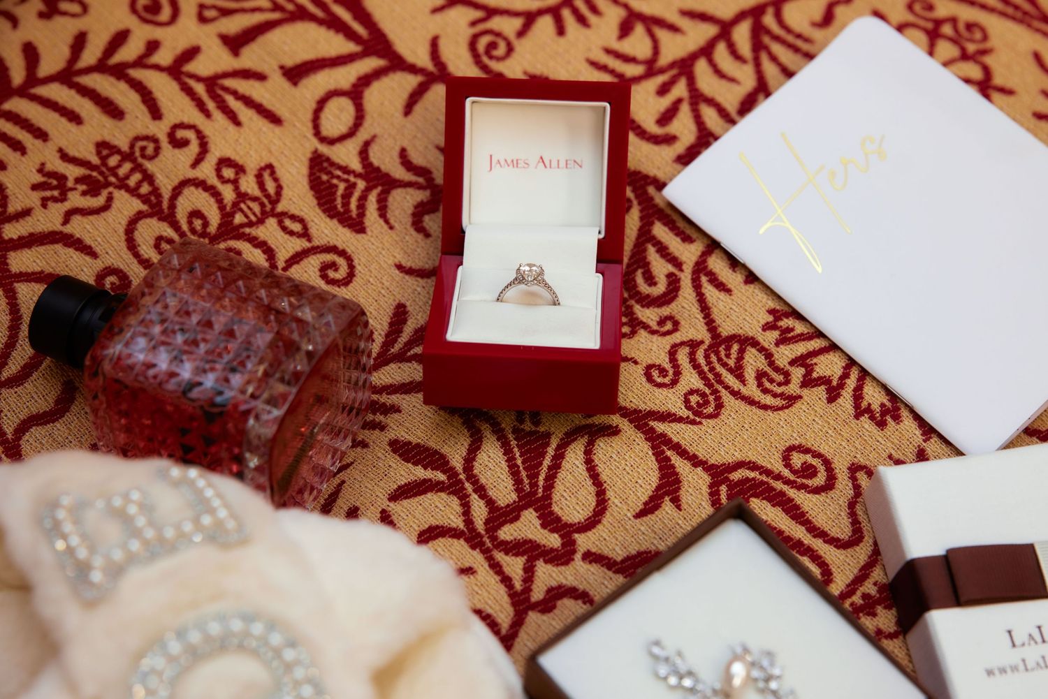 Red and white damask pattern fabric with scattered white paper notes and cards in soft lighting.