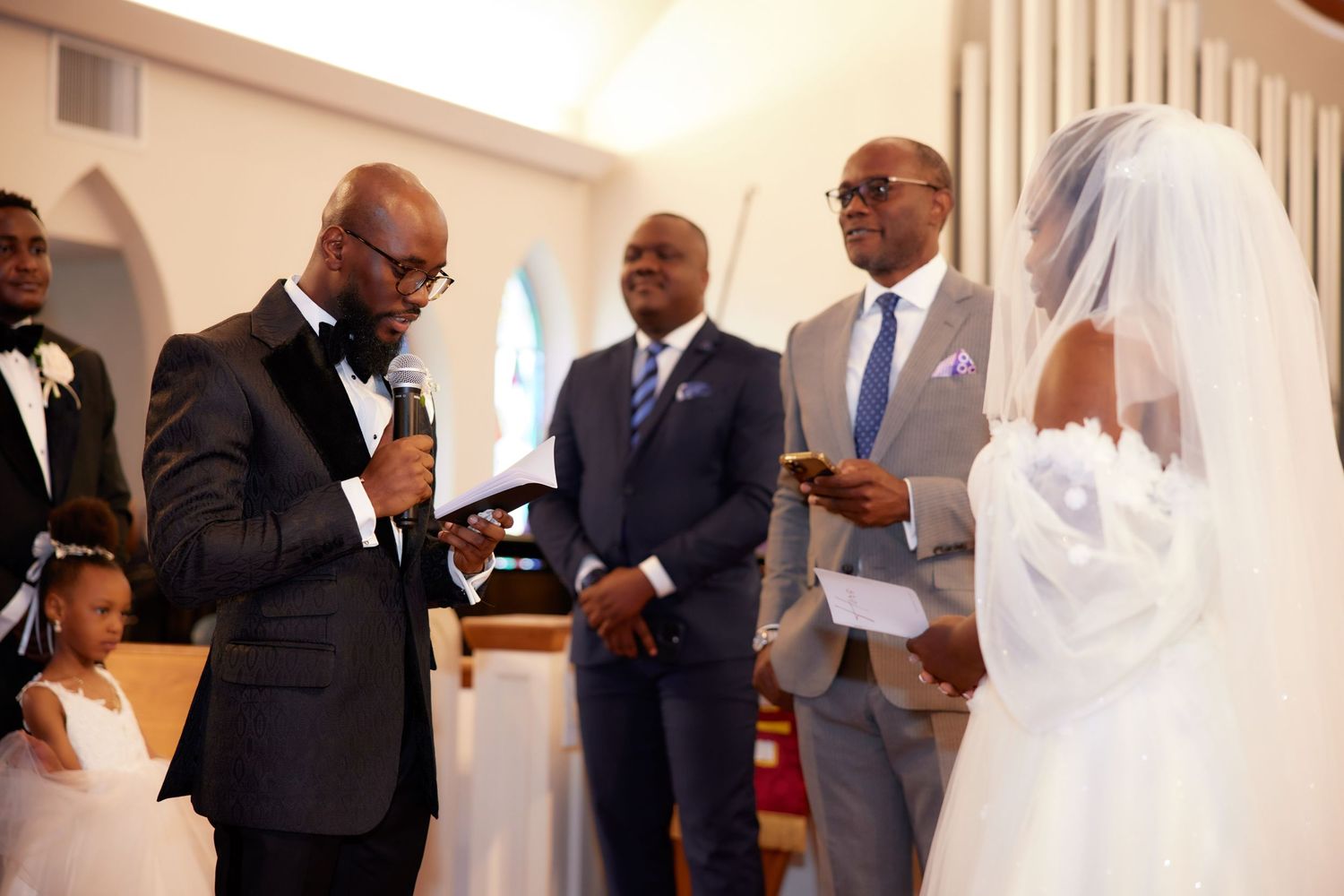 A solemn wedding ceremony takes place inside a bright church with elegant arched architecture.