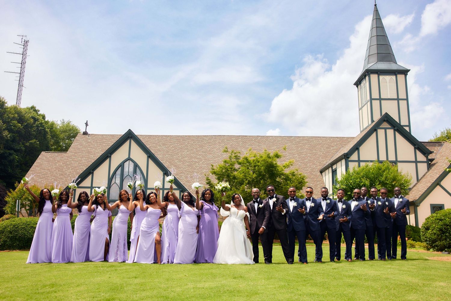 Wedding party poses from left to right in classic church garden photo formation wearing lavender and black attire.