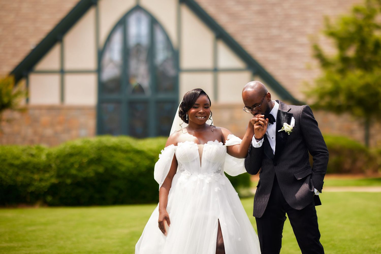 Happy newlyweds share a joyful moment together on their wedding day outside a church with Tudor-style architecture.