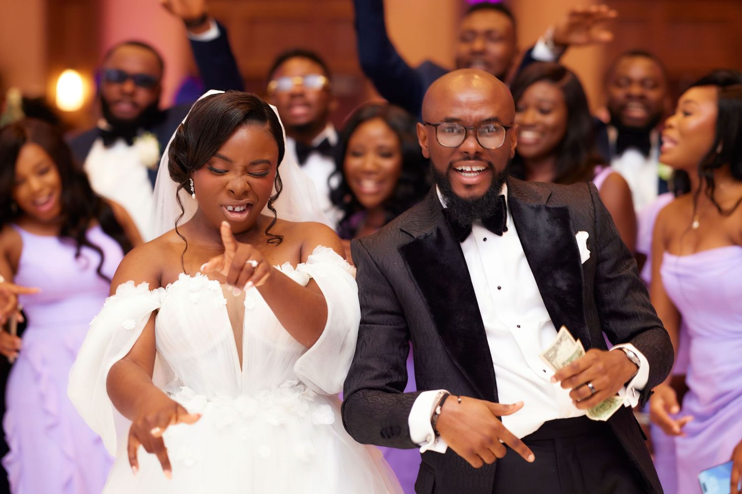 Wedding reception celebration with guests dancing and enjoying themselves in a dimly lit ballroom.