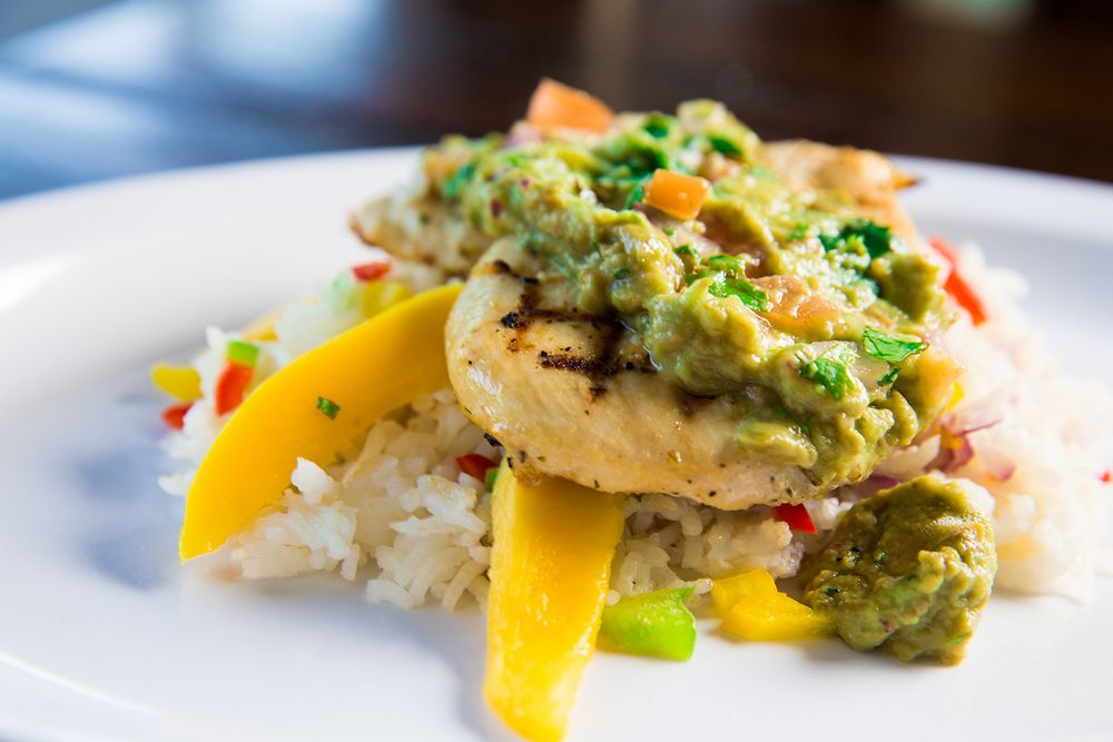 Gourmet dish with rice and avocado sauce garnished with yellow peppers.