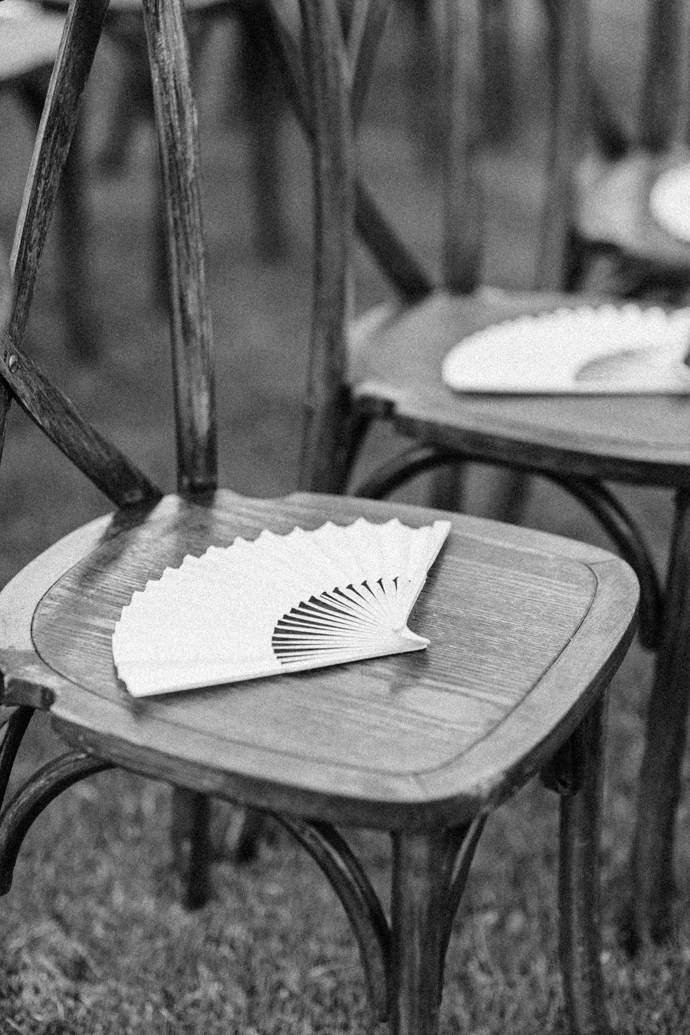 A sequence of photos showing a decorative white hand fan being placed on a wooden chair seat outdoors.