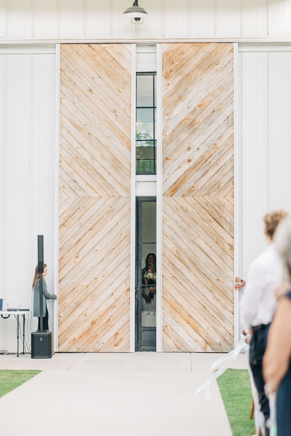 Modern barn venue features diagonal wood paneling and white walls with industrial lighting.