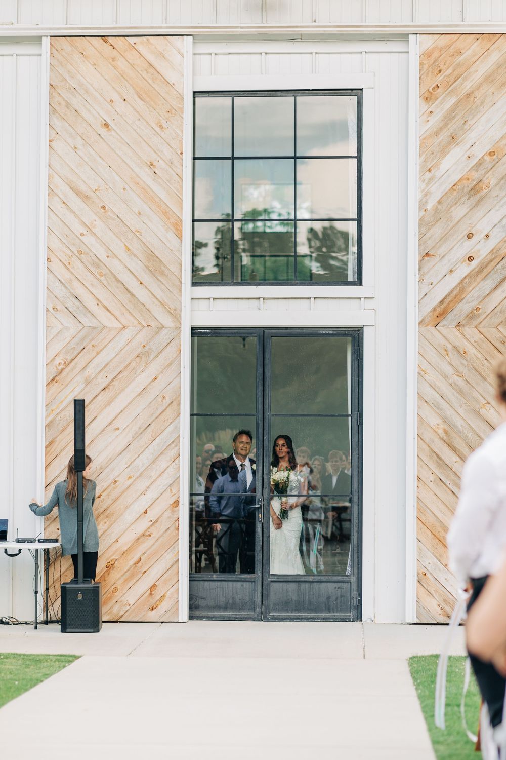 Modern building exterior features diagonal wood paneling design and large glass windows with reflection.