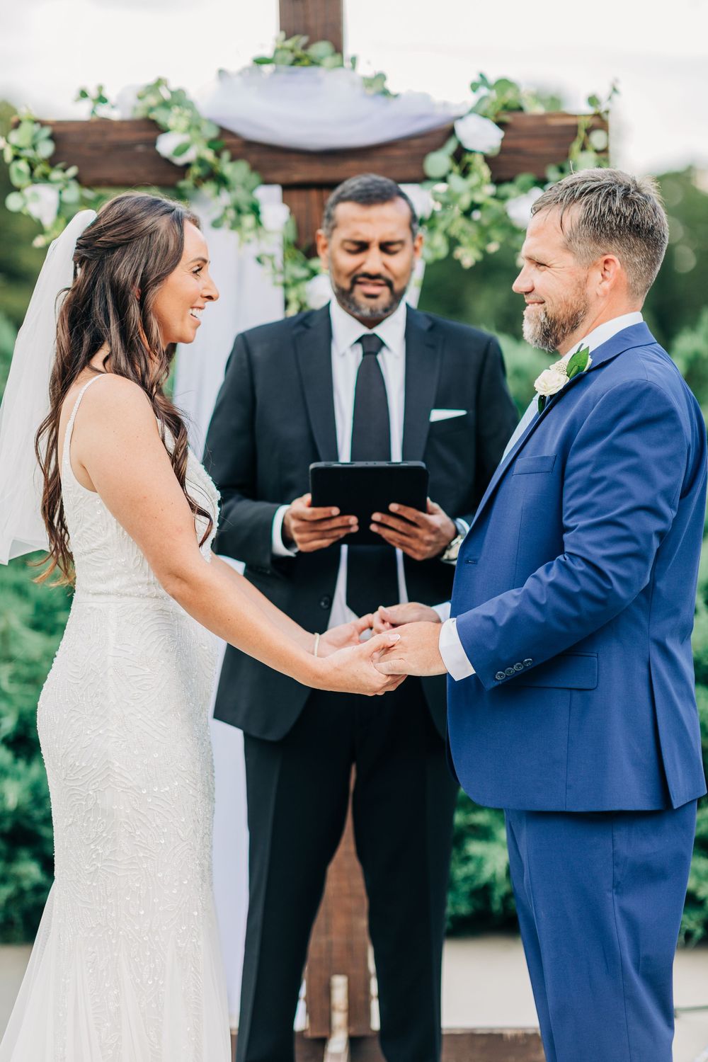 A series of intimate moments during an outdoor wedding ceremony showing the exchange of rings and vows.