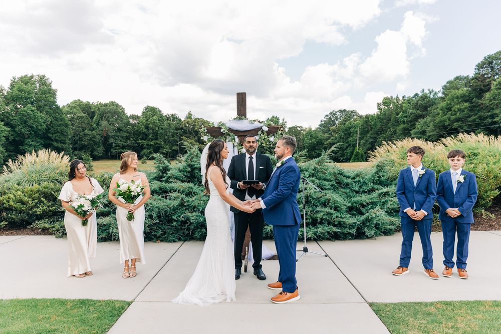 Wedding party in blue suits and white dresses posing for photos on a summer day.