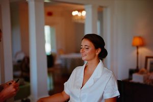 A bride wearing a white robe is getting ready for her wedding day in an elegant hotel room.