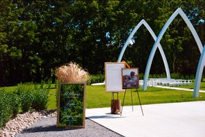Modern architectural art installations with white metal arches and decorative elements line a landscaped garden path.
