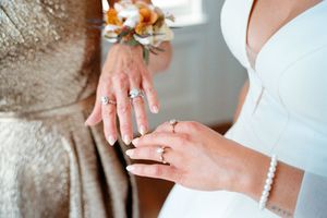 Close-up shot of someone putting on an elegant white pearl bracelet against a soft background.