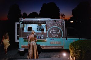 A vintage blue food truck serving customers at an outdoor event during twilight hours.
