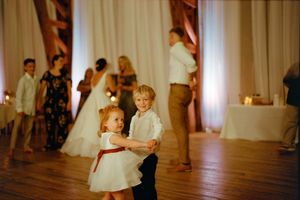 Panoramic view of a wedding reception in a light-filled room with wooden floors and white curtains.
