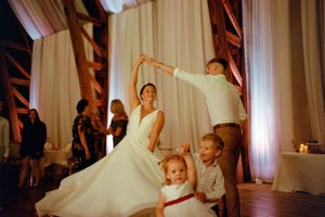 Wedding celebration with dancing as white dress twirls on dance floor with children joining in the fun.