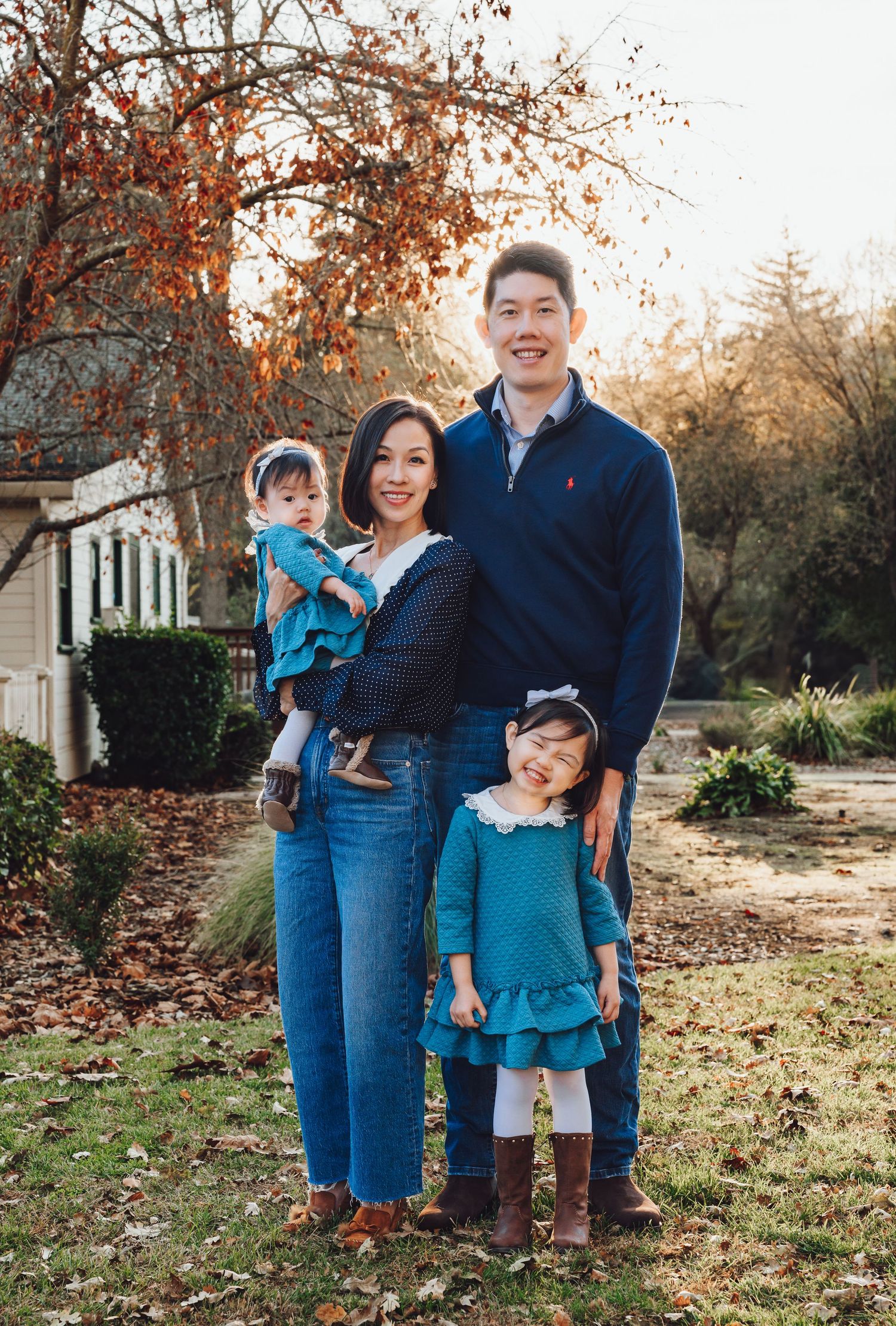 Family wearing coordinating blue and denim outfits poses together during an autumn outdoor photoshoot.