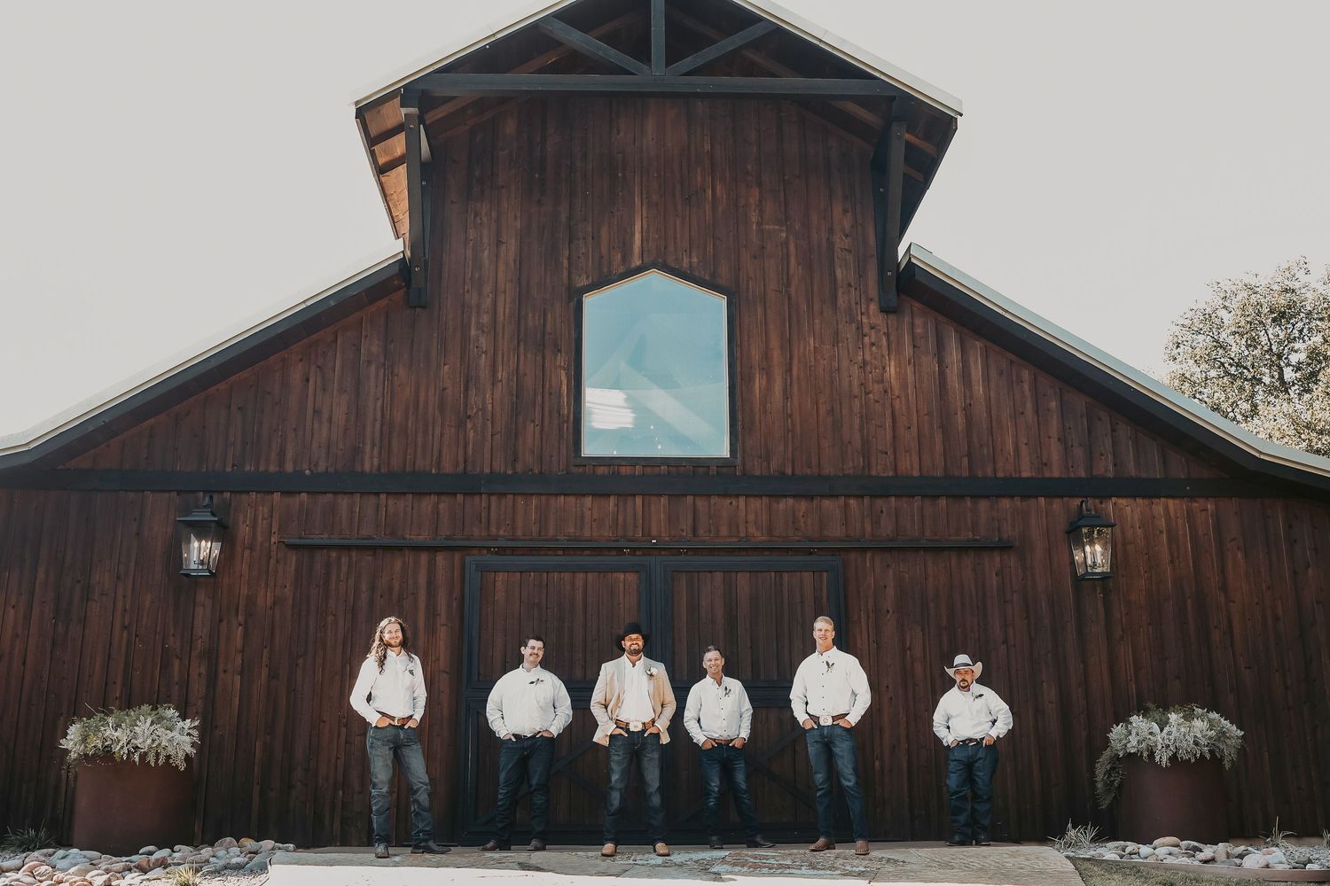 Rustic Texas wedding groomsmen photo in front of Whispering Oaks barn