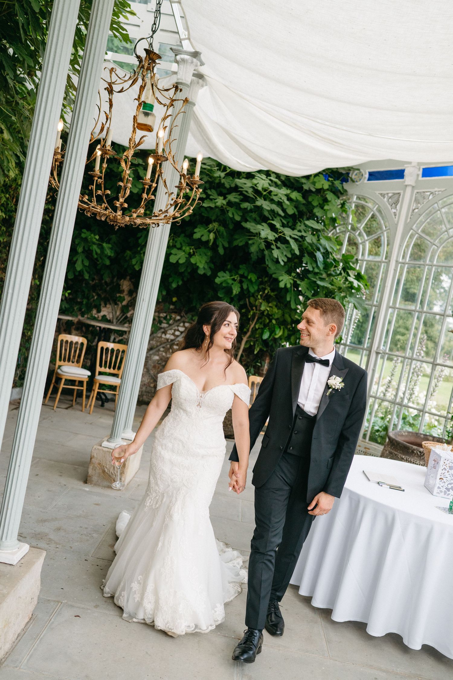 Dancing couple in formal attire performing a romantic dip on a hardwood floor inside an elegant library with chandeliers.