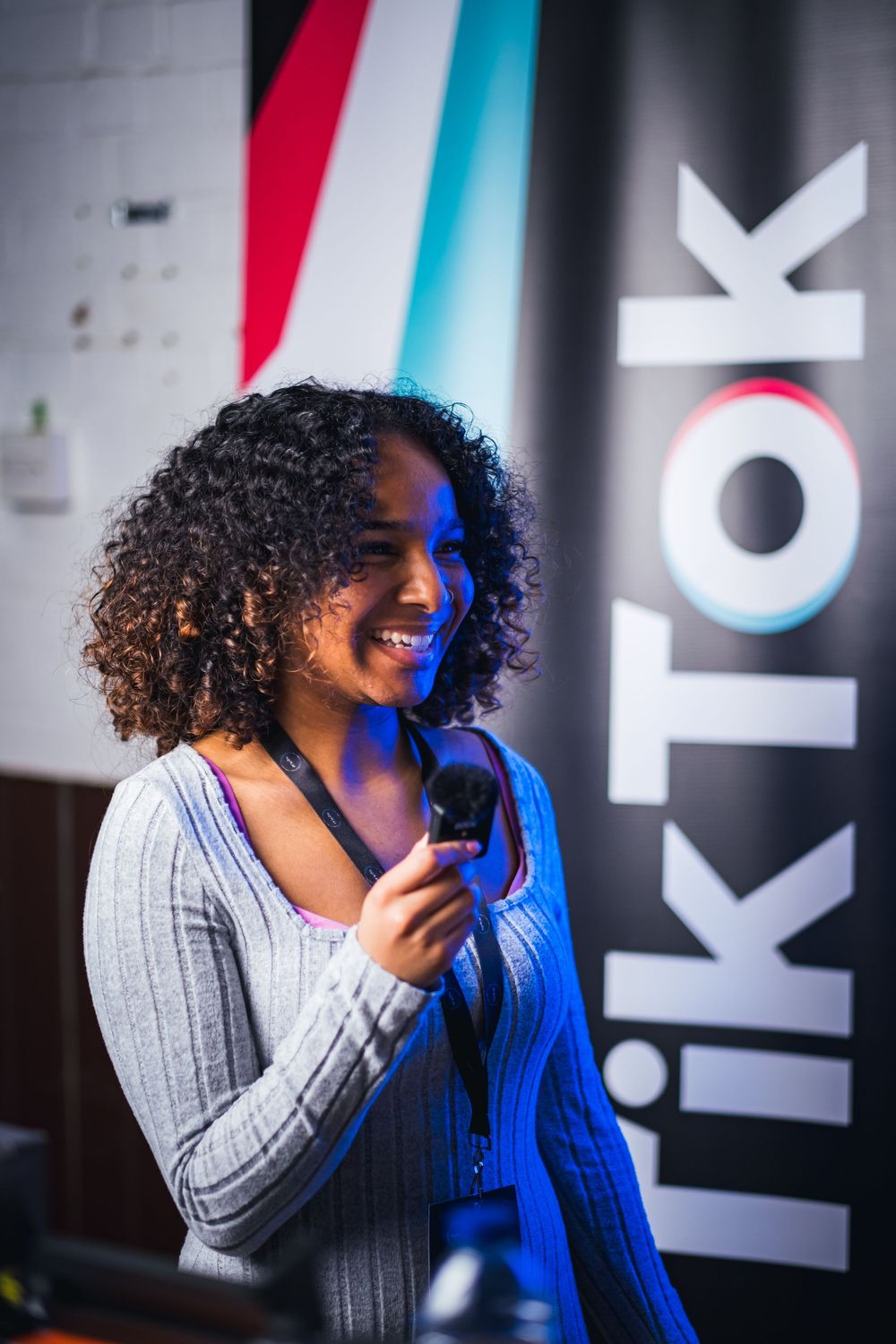 Presenter speaking against a backdrop with red and blue lighting effects.