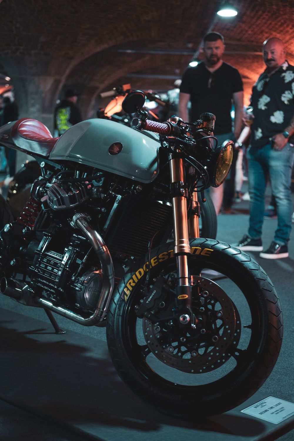 Custom motorcycles on display in a dimly lit venue with ambient lighting.