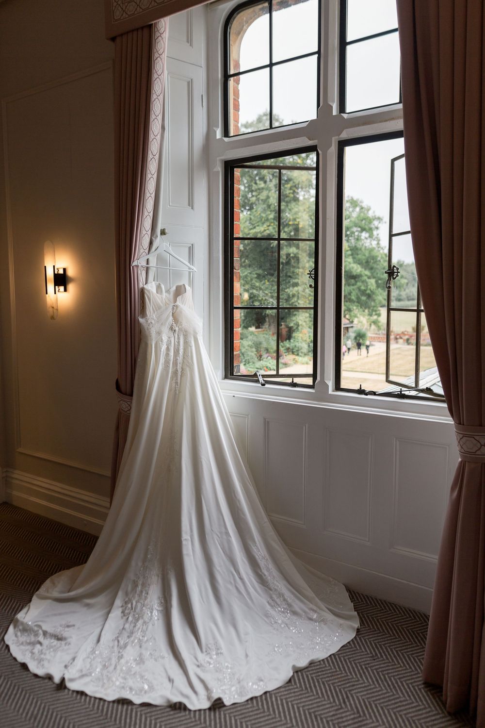 White wedding dress displayed by a window with natural light streaming in.