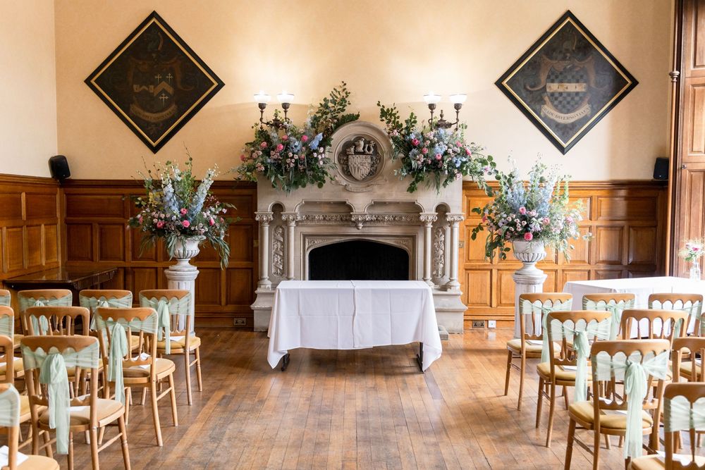 Elegant wedding reception venue with wooden chairs and decorative wall art arranged in a panoramic view.