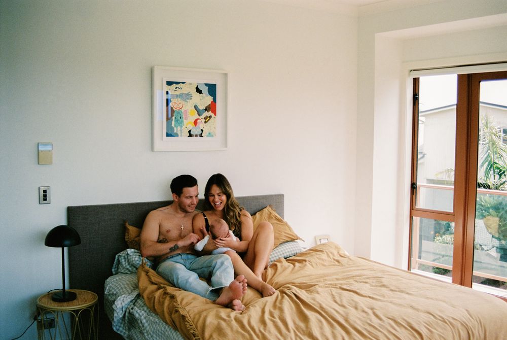 Couple relaxing together on unmade bed near window in cozy bedroom.