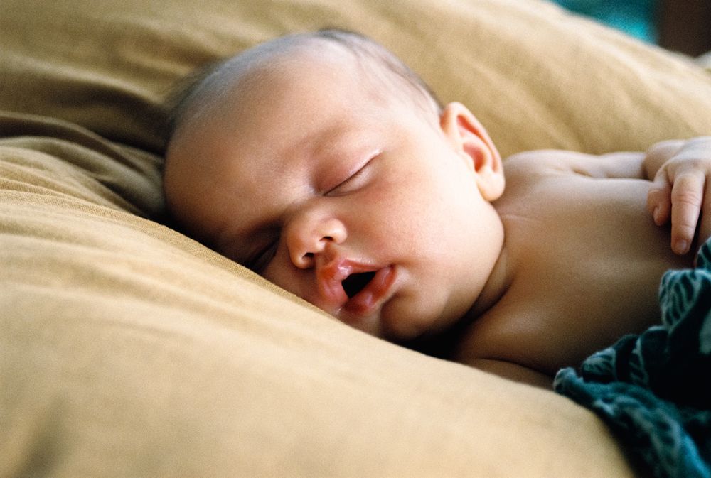 Close-up of an infant sleeping peacefully on soft bedding.